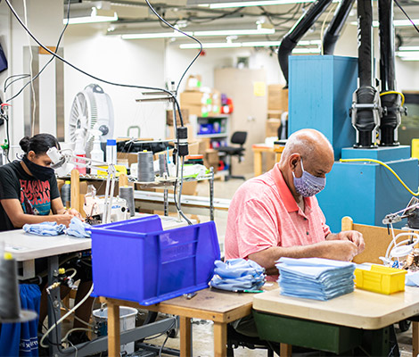 Two employees work diligently on sewing products.